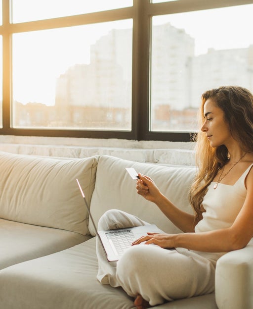 Young Woman relaxing on sofa and Shopping Online With Credit Card and Laptop