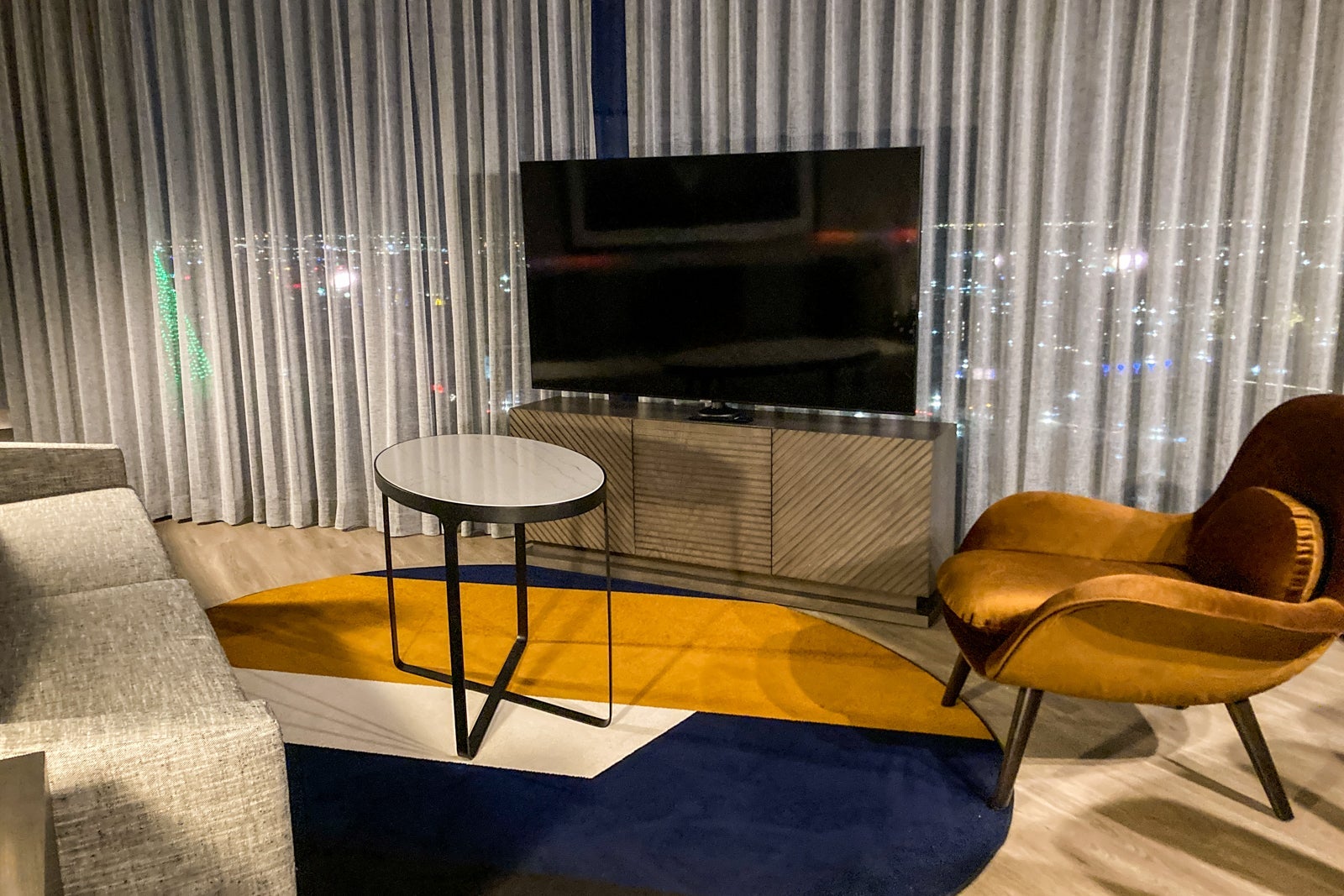 a TV, table and chair in a suite's living room