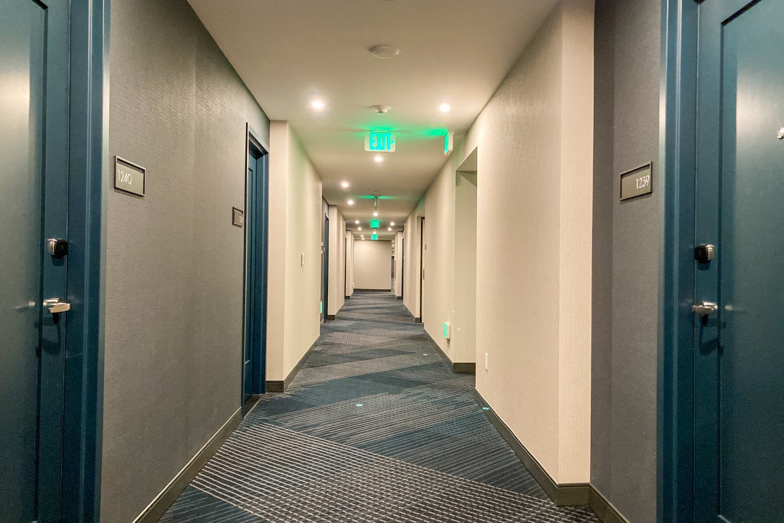 looking down a carpeted hallway at a hotel,, showing blue and green color patterns