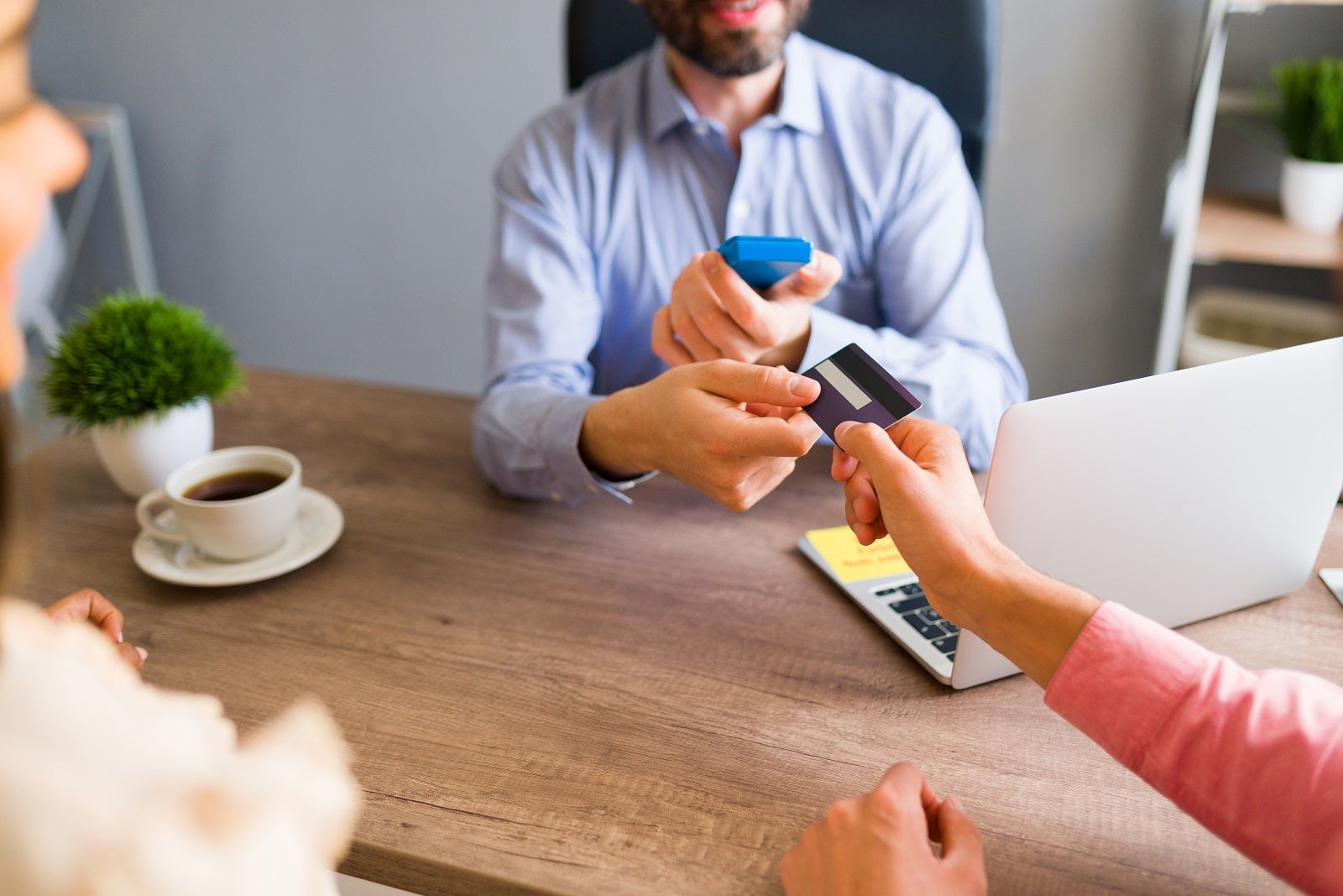 A person's arm handing a credit card to a travel agent to make a booking