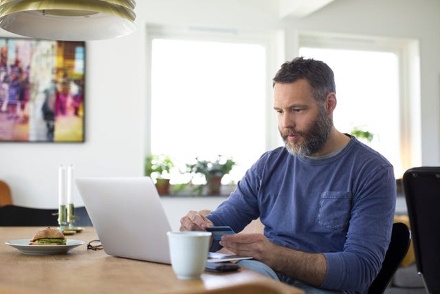 A man sits at his computer to read information about his credit card