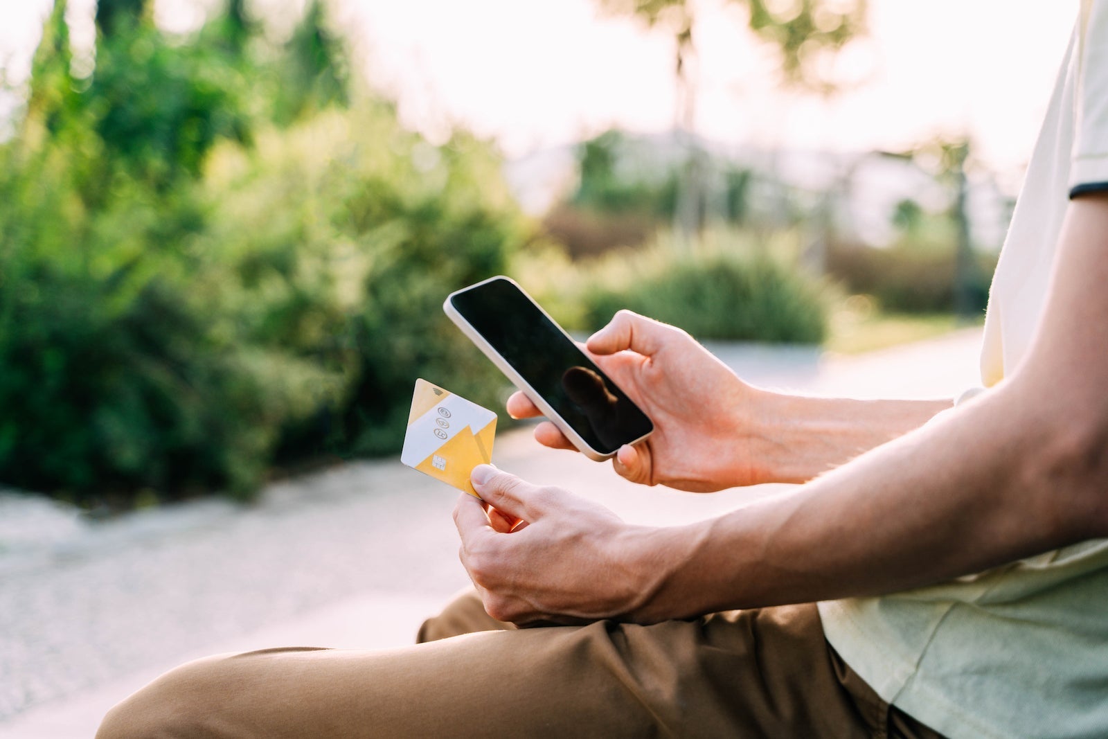 An unseen person holds a credit card while looking at a smart phone
