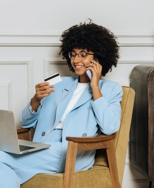 a woman has a laptop sitting on her lap while making a phone call