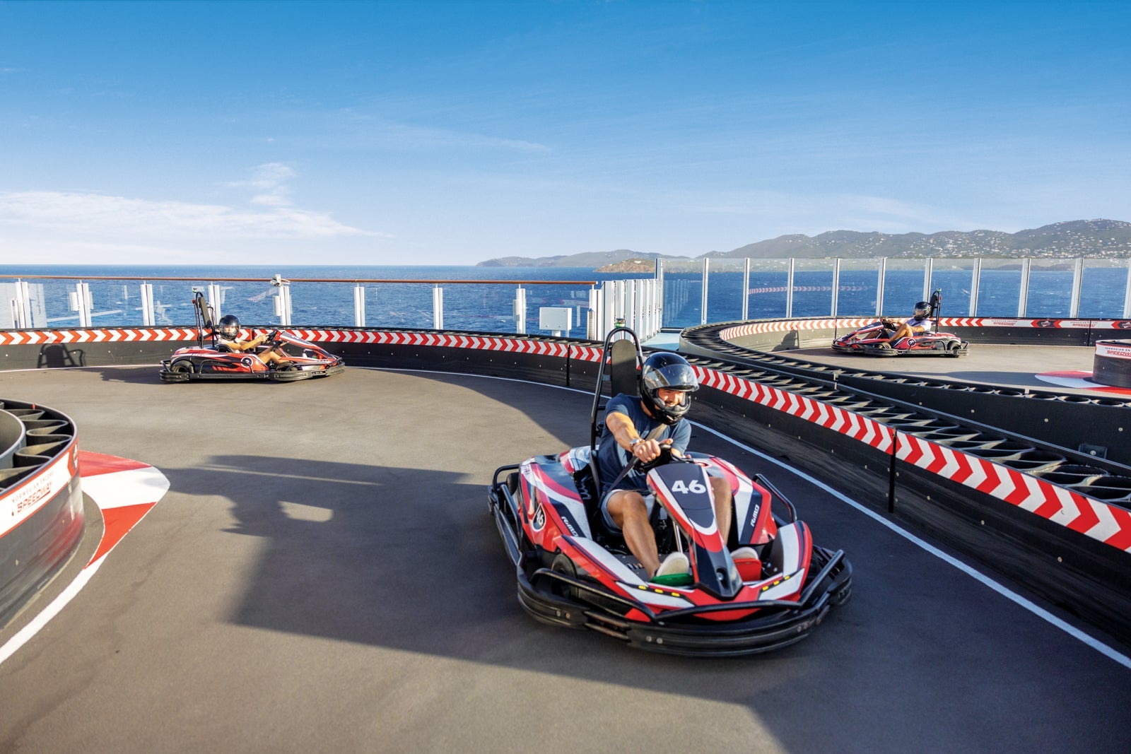 Cruise passengers riding go-karts on the top deck of a ship