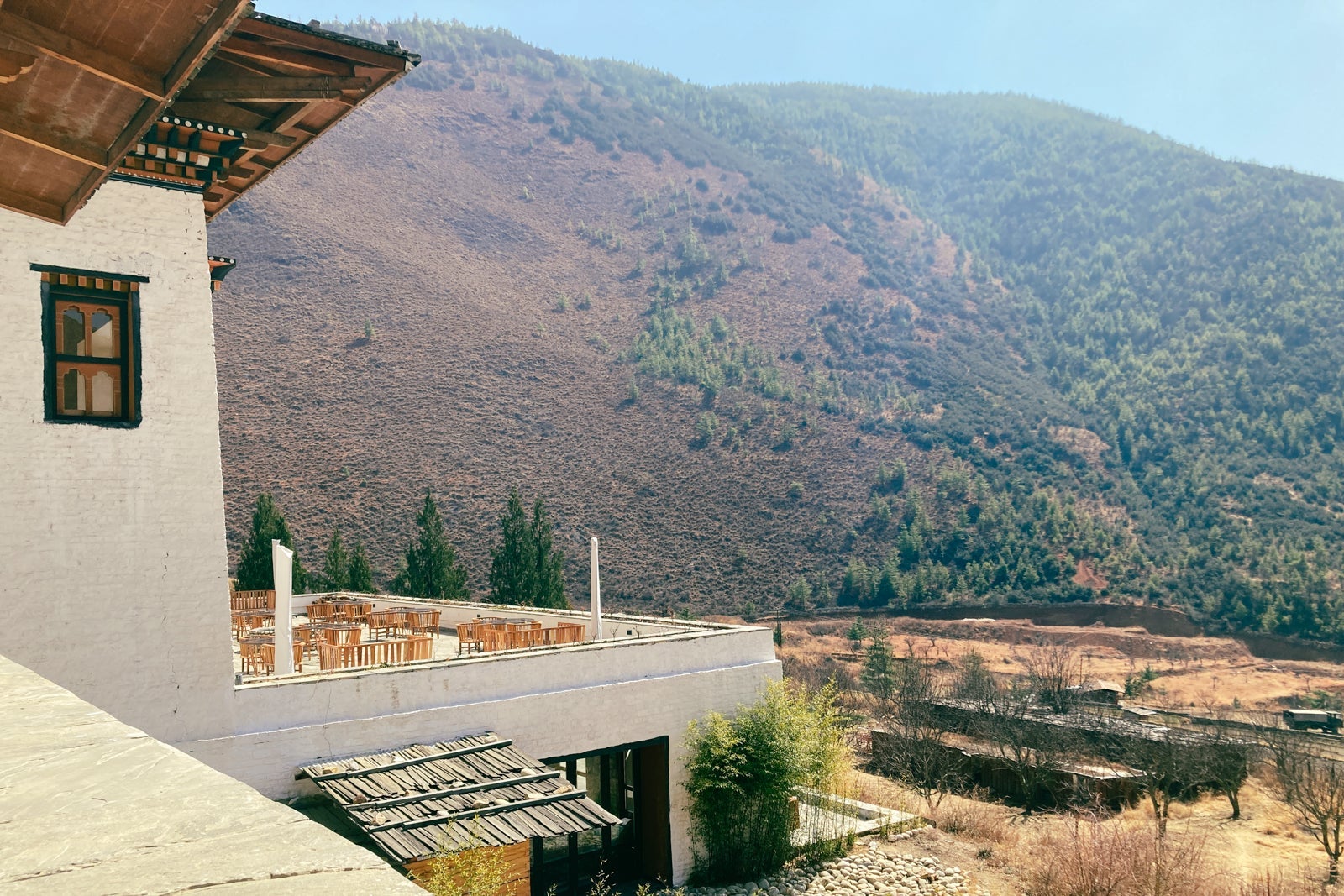 a restaurant terrace behind a hotel is visible, looking out over hills in a secluded area
