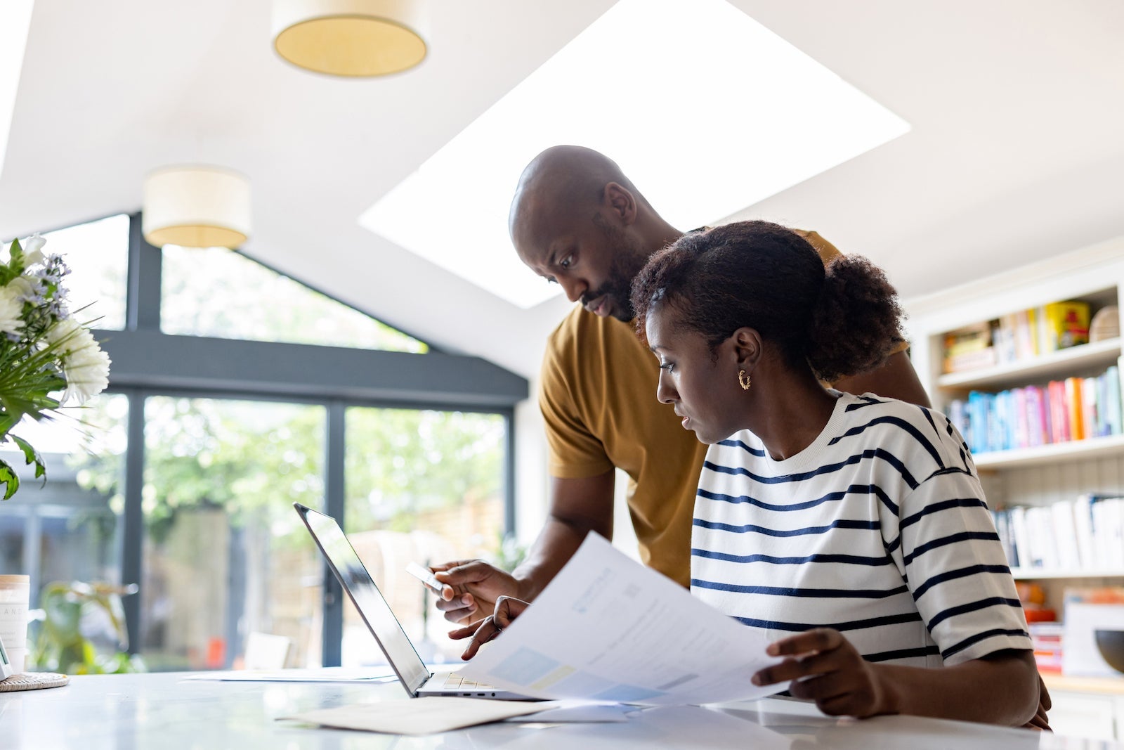A couple looks at documents and a computer while paying bills