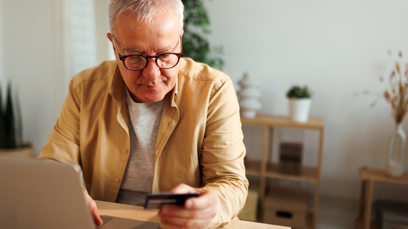 Senior man holding credit card while using laptop for online shopping