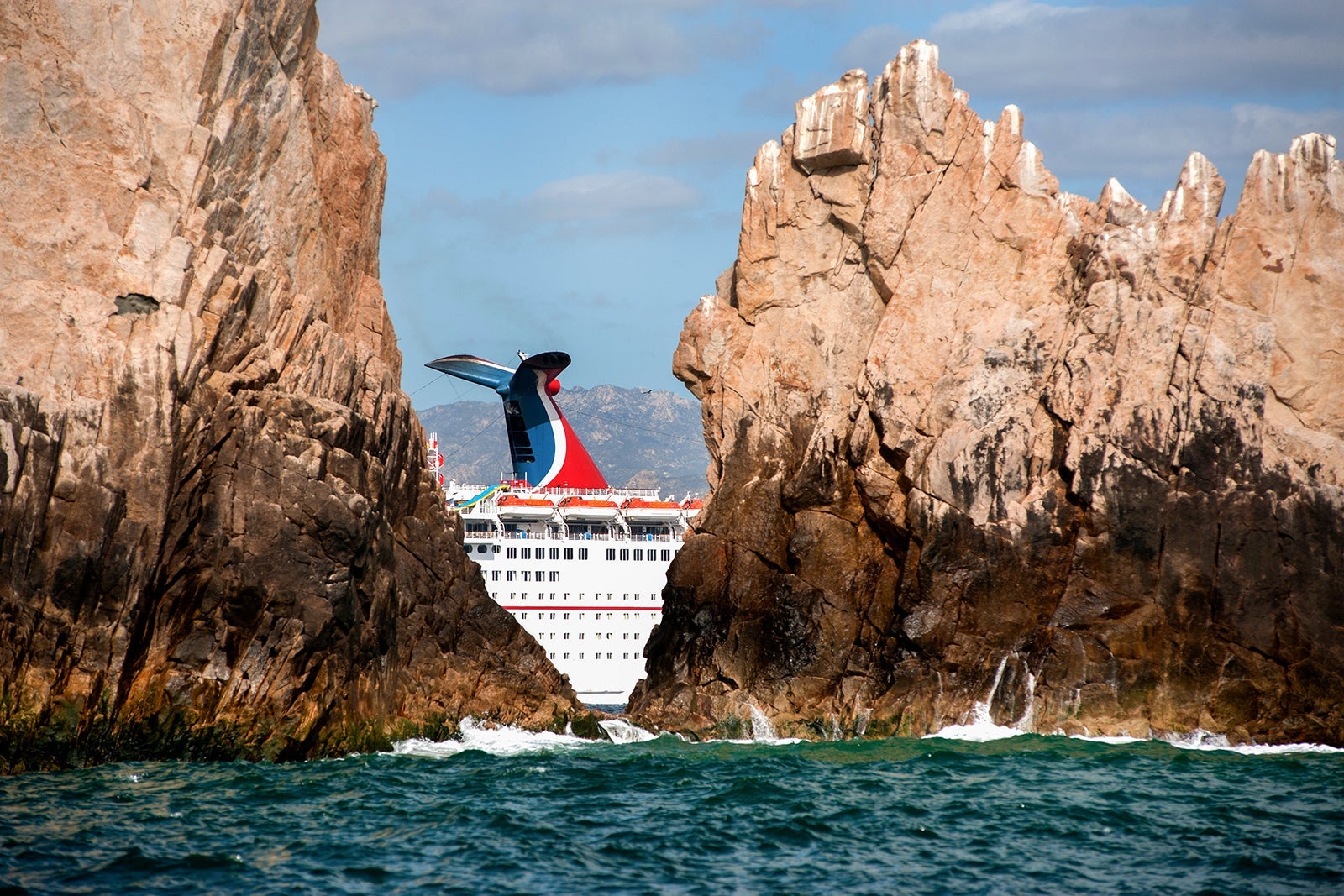 The funnel of a cruise ship passing between rocks in Cabo San Lucas, Mexico