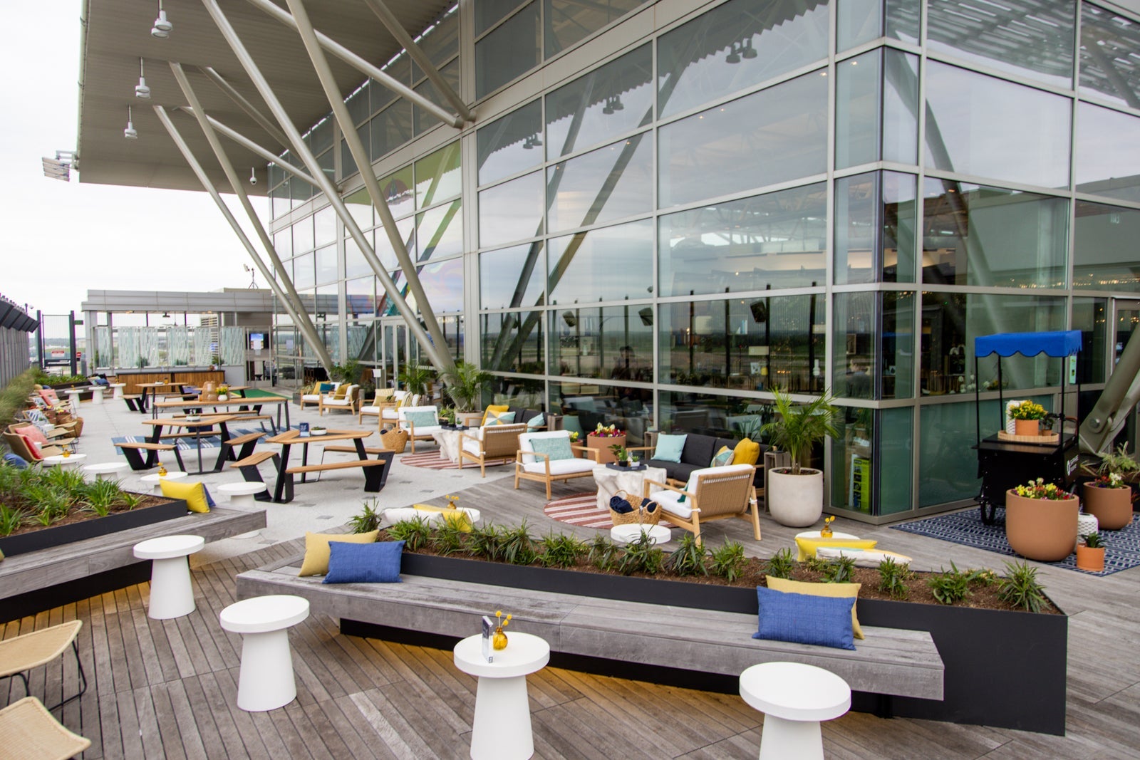 multiple seating types are visible on an outdoor patio at an airport, part of a lounge inside