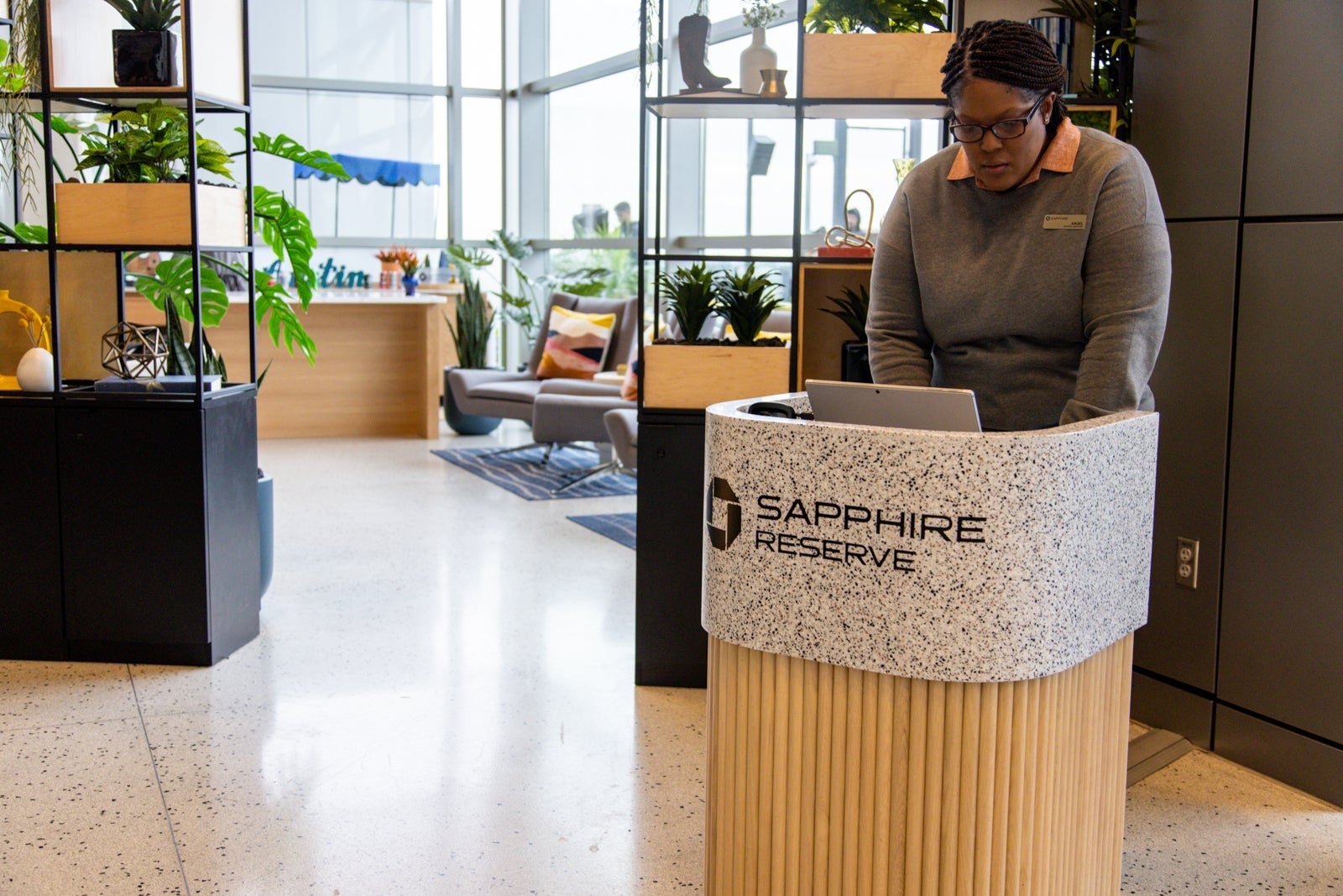 an employee stands at a check-in desk for an airport lounge