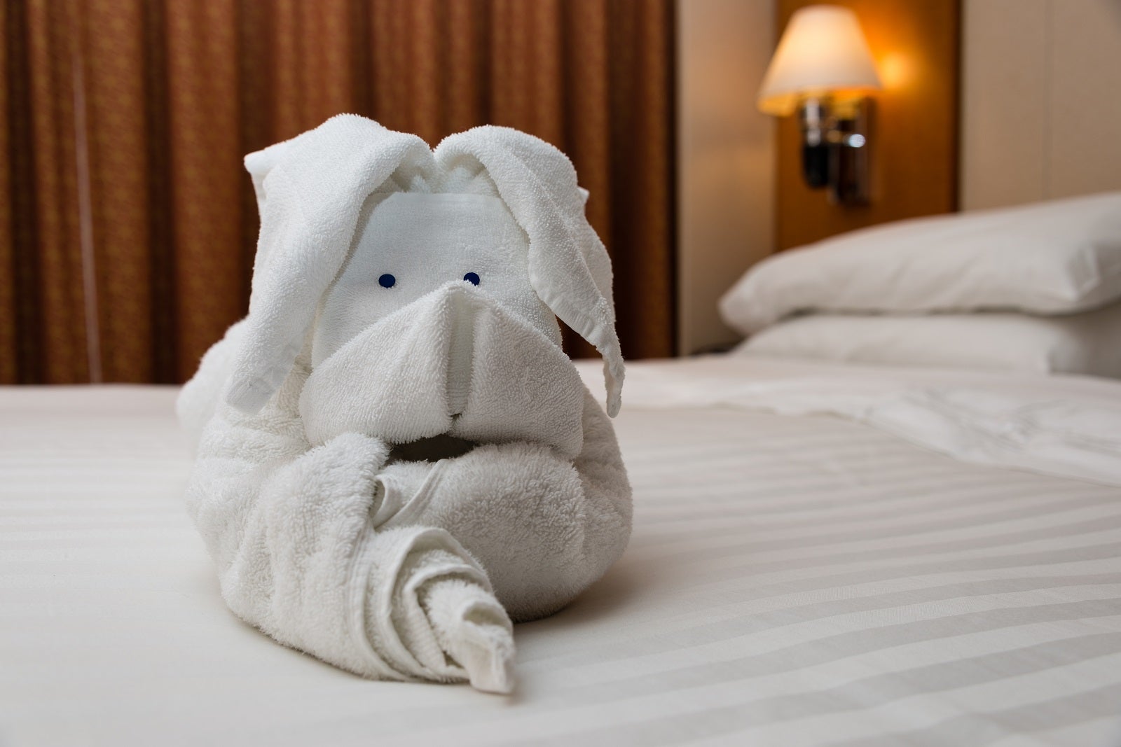 A towel animal dog sits on a bed with a white comforter