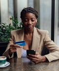 Businesswoman with credit card and smart phone sitting at cafe
