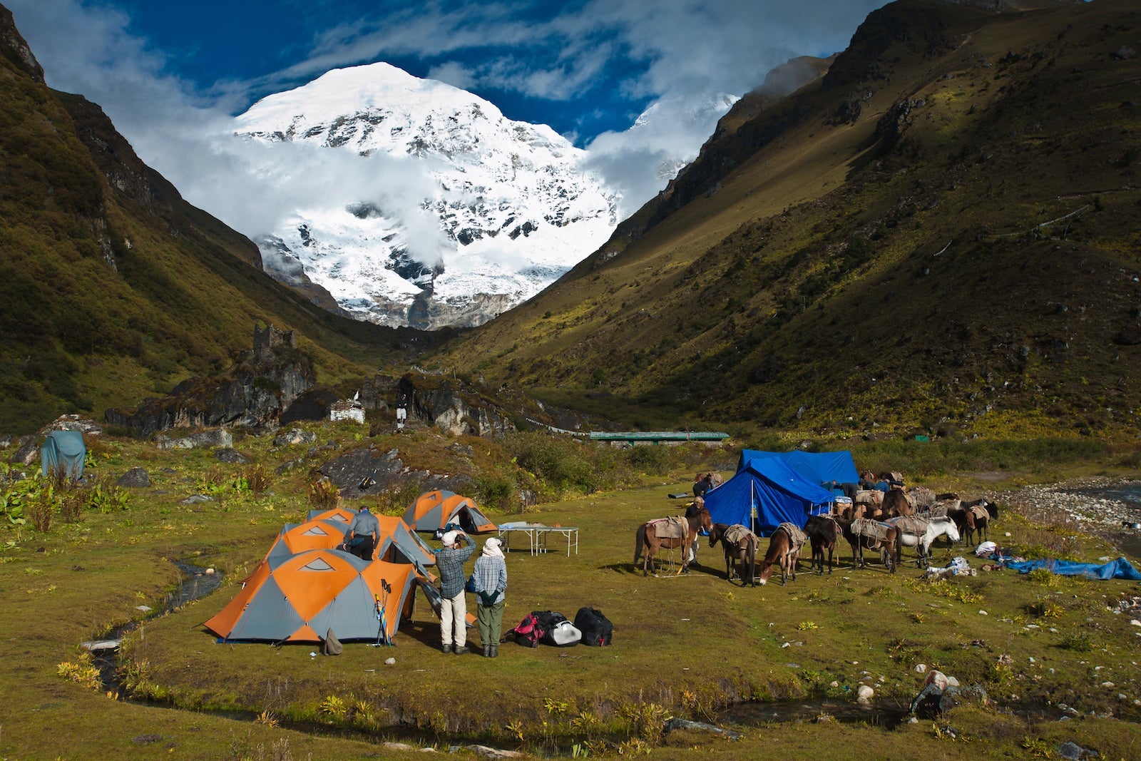 tents, hikers and mules are visible at a base camp near mountains