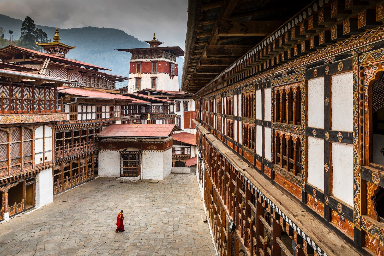 A traditional Buddhist monk is seen walking through a courtyard inside a monastery in Bhutan