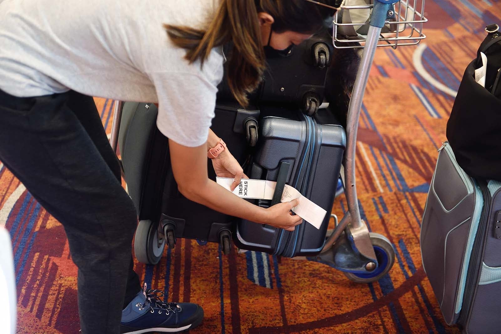 A person putting a luggage tag on their suitcase