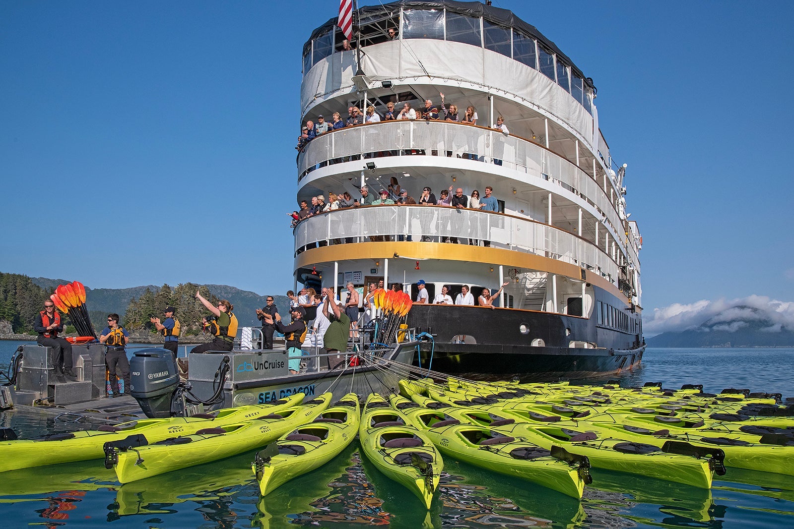 An expedition cruise ship with green canoes fanned out behind it