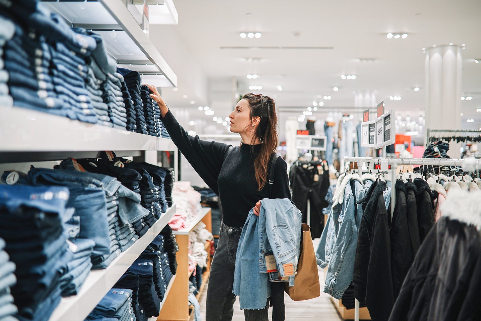 A woman shopping in a clothing store, looking at jeans