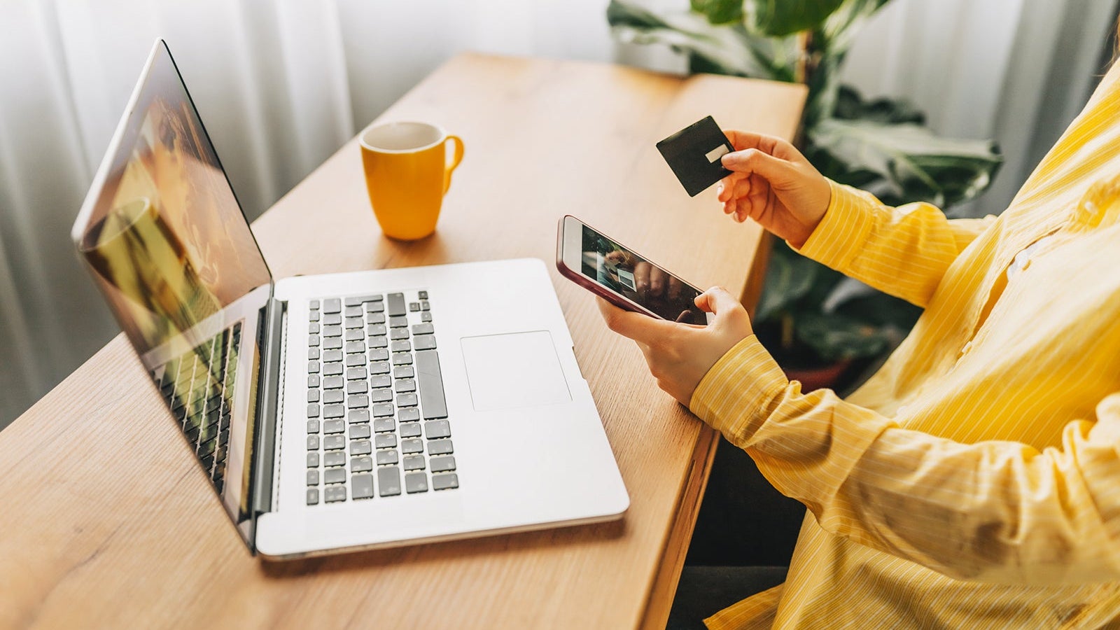 Shot of pretty young woman shopping online with credit card and laptop while sitting on the floor at home.