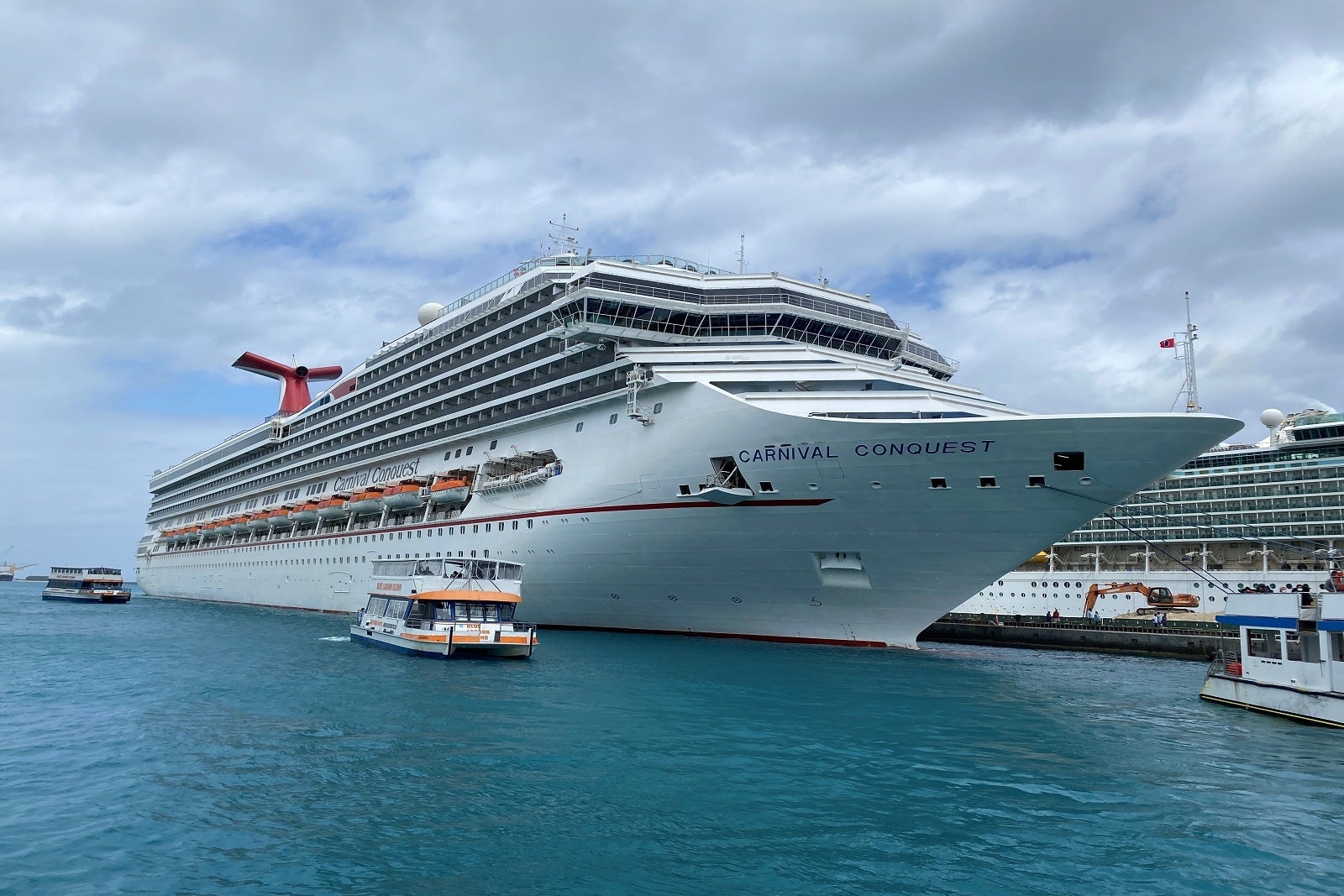 A cruise ship with a red hull docked in port