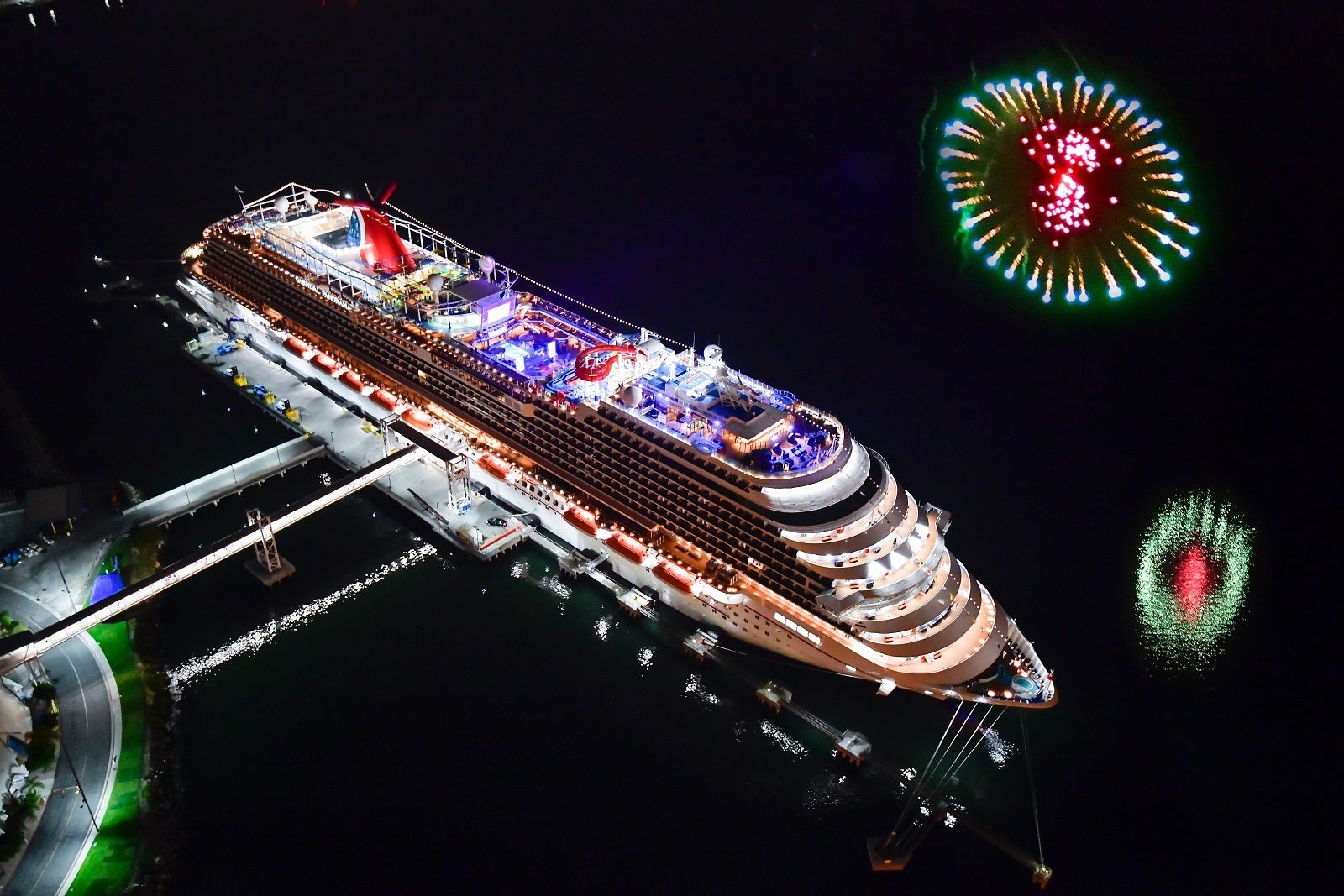 Aerial photo of a cruise ship lit up a night with dark water all around it