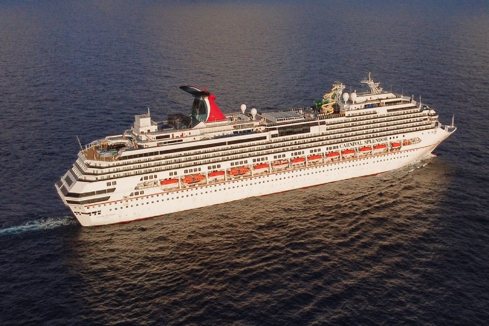 A cruise ship with a red, white and blue funnel sailing on dark blue water