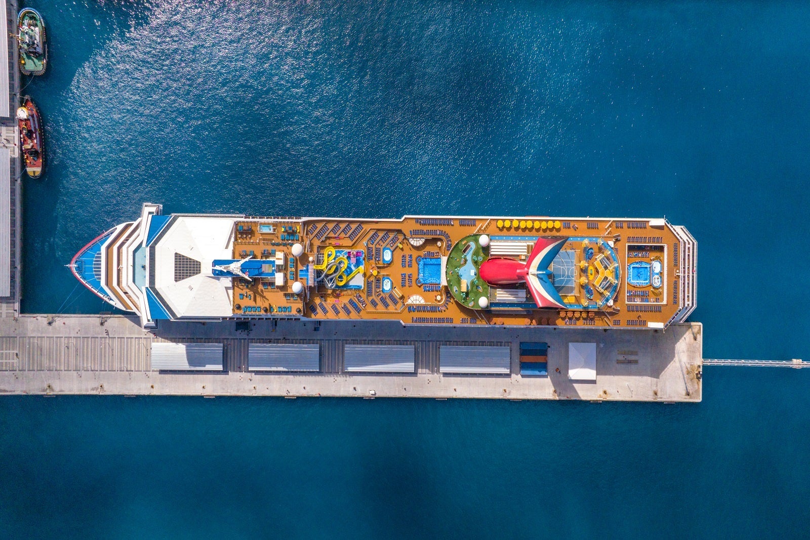 An aerial view of the top deck of a cruise ship docked at a pier