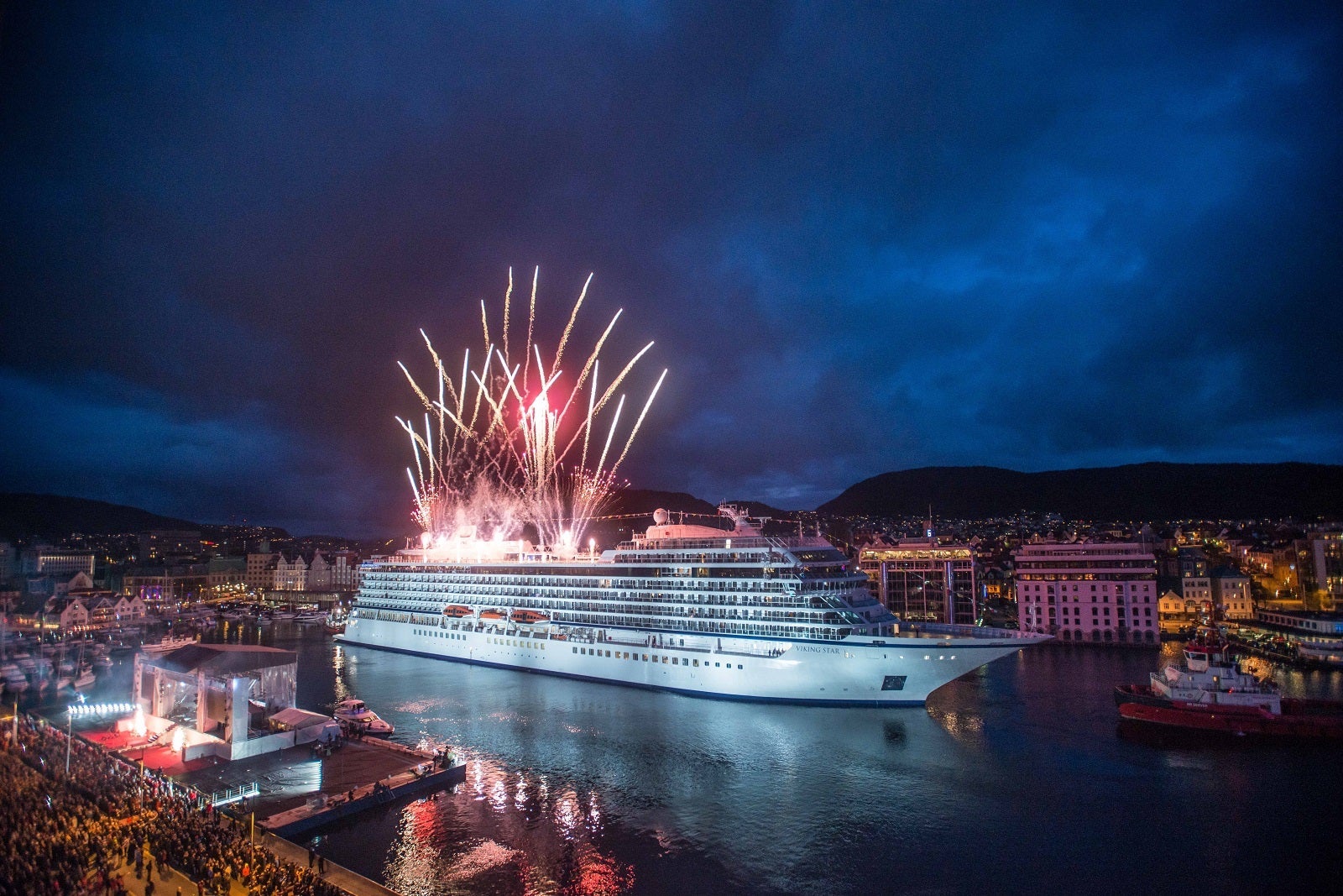 A cruise ship docked in Bergen, Norway, at night with fireworks in the background