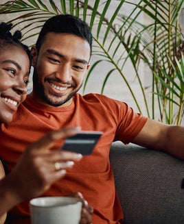 Shot of a young couple sitting together in the living room and using a digital tablet for online shopping