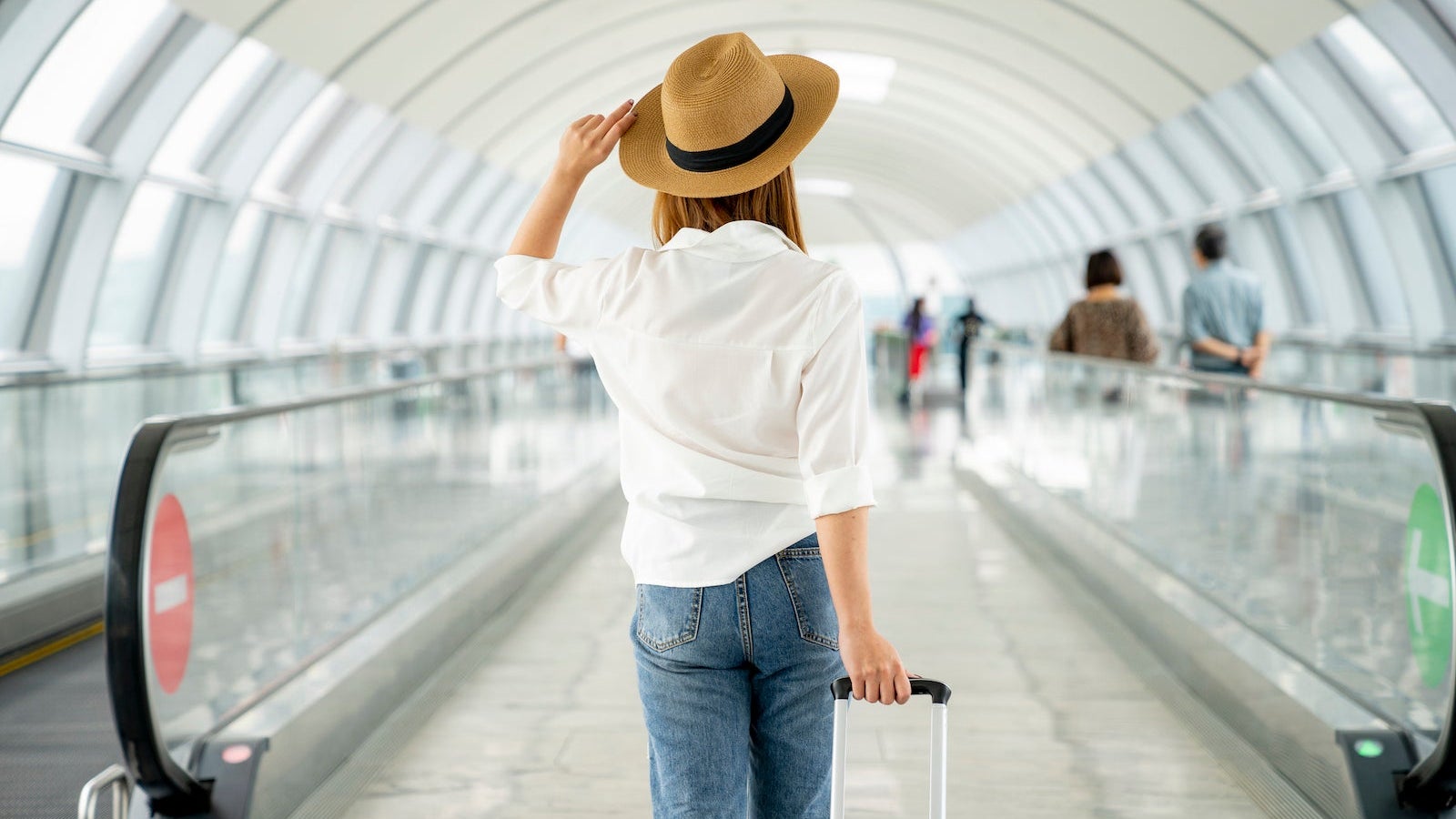 Young casual female traveler with suitcase at airport