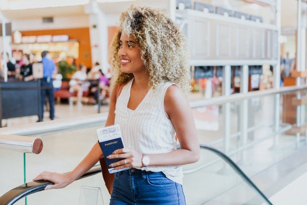 Cheerful international traveler ascends airport escalator