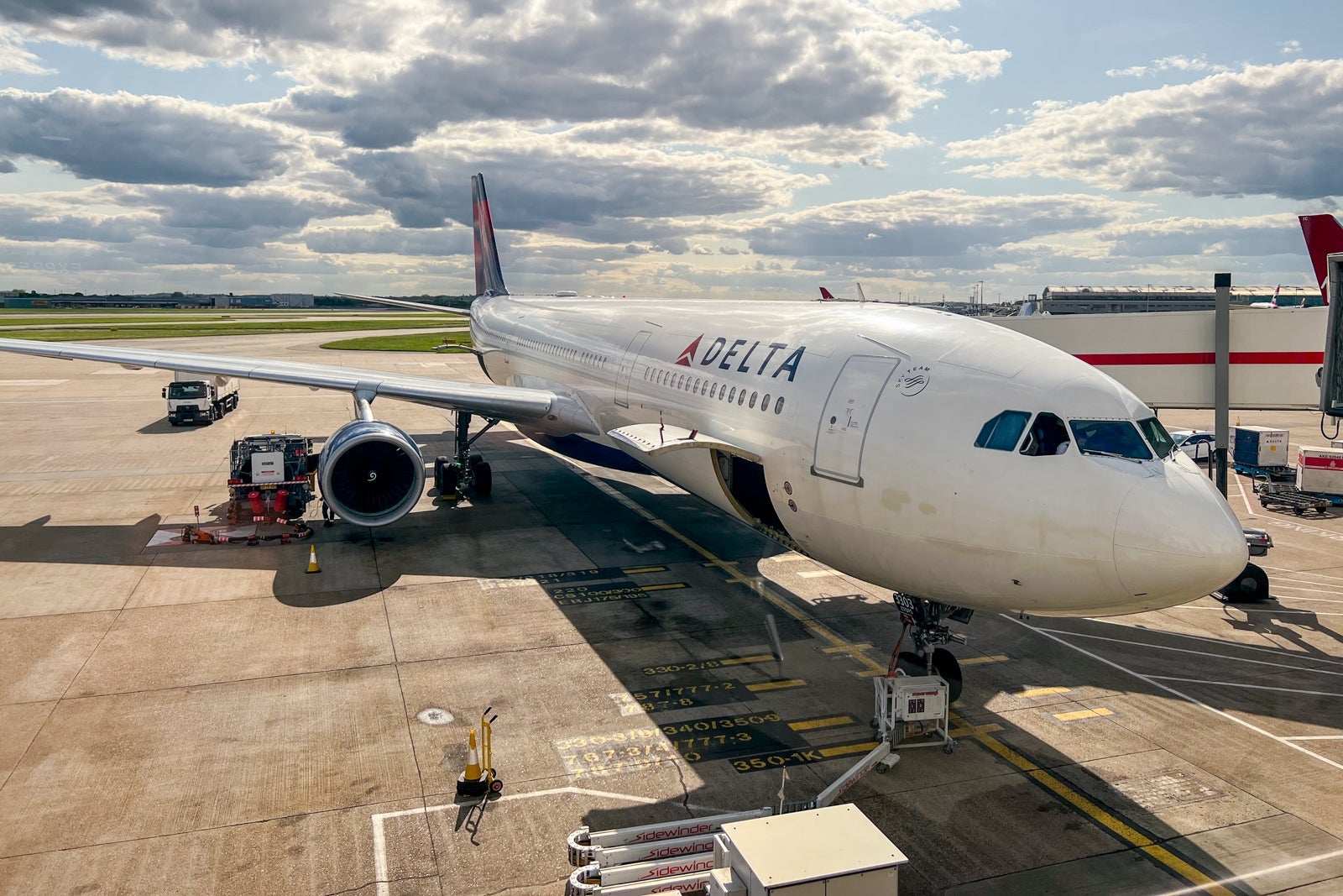 A Delta airplane on the tarmac with a cargo door open