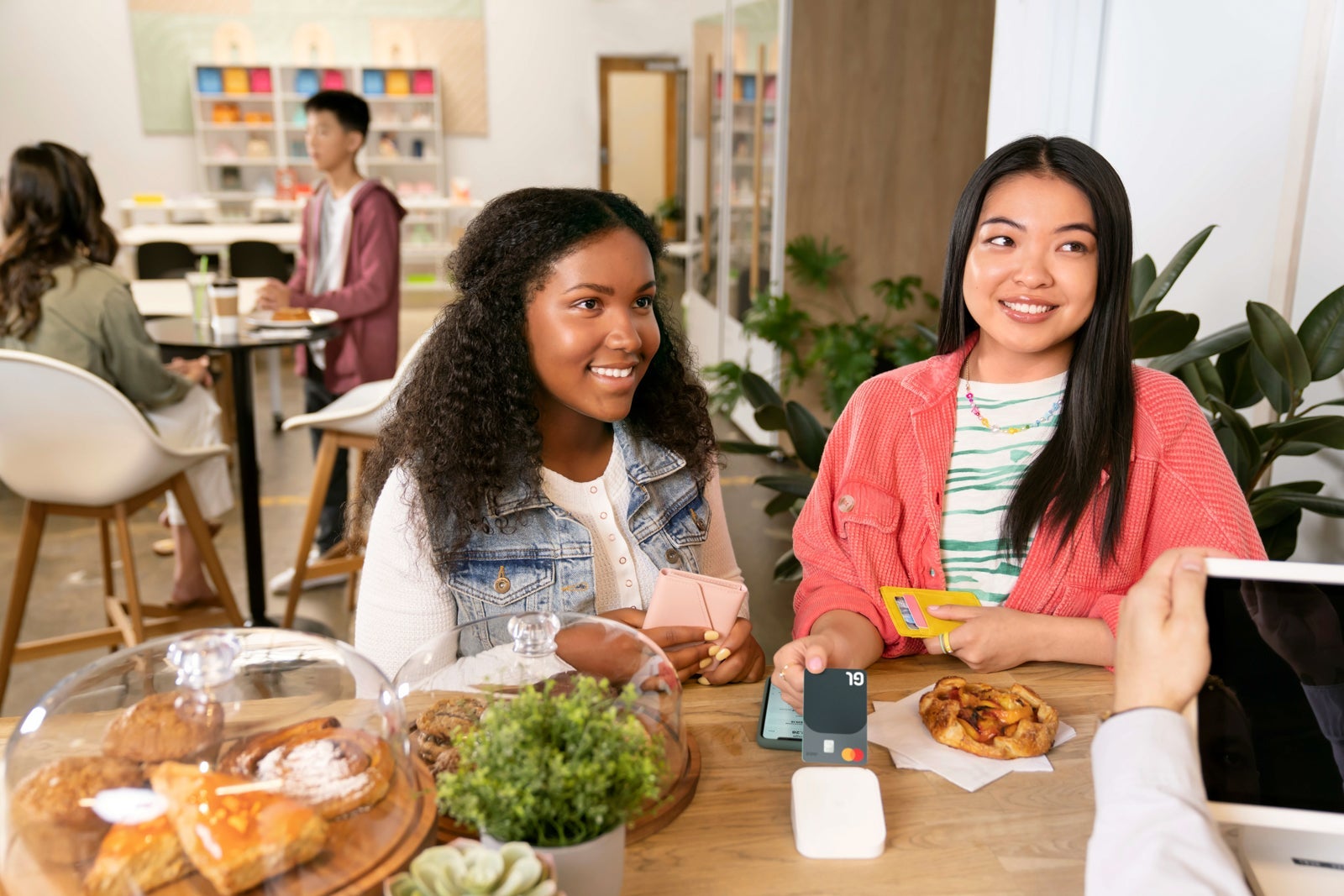 Two teenagers paying at a restaurant with the Greenlight card