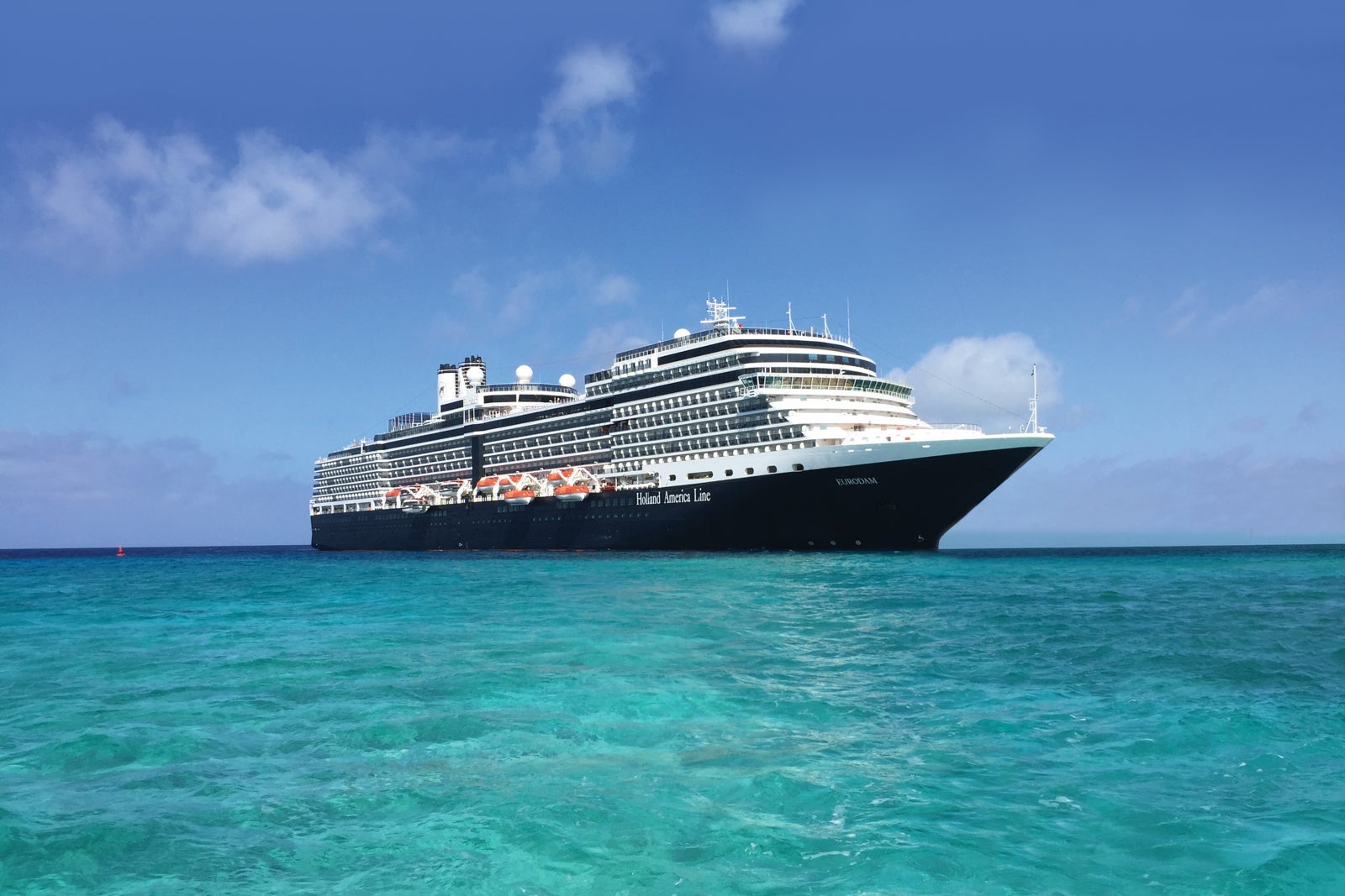 A Holland America ship anchored on clear, turquoise water