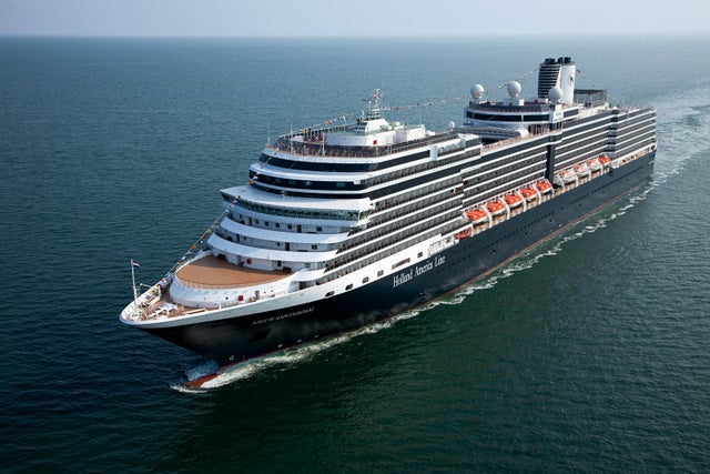 A Holland America ship sailing, creating white waves on blue water