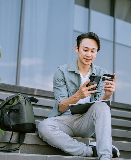 Man using a cell phone and tablet outside