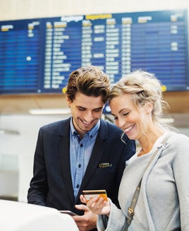 Happy business people looking at credit card in airport