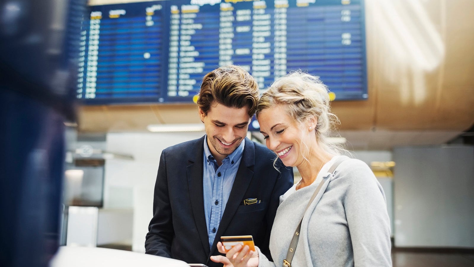 Happy business people looking at credit card in airport