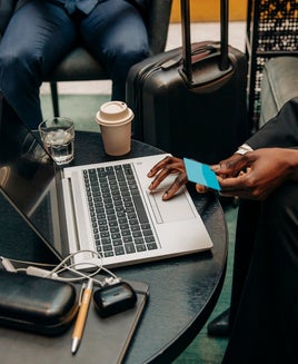 Young businesswoman holding credit card while using laptop at hotel lounge