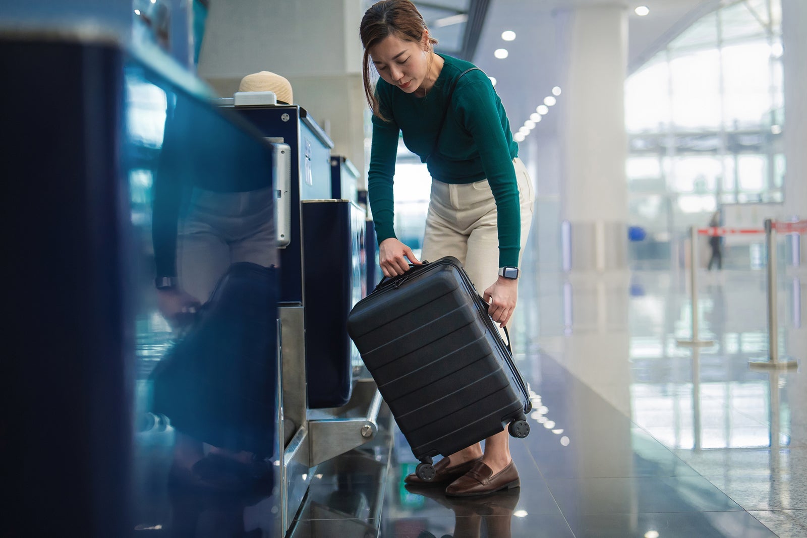 A woman putting her suitcase on a luggage scale while checking in for a flight