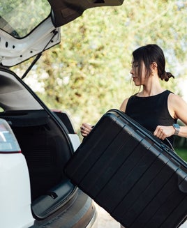 woman loading luggage into car, getting ready for a road trip