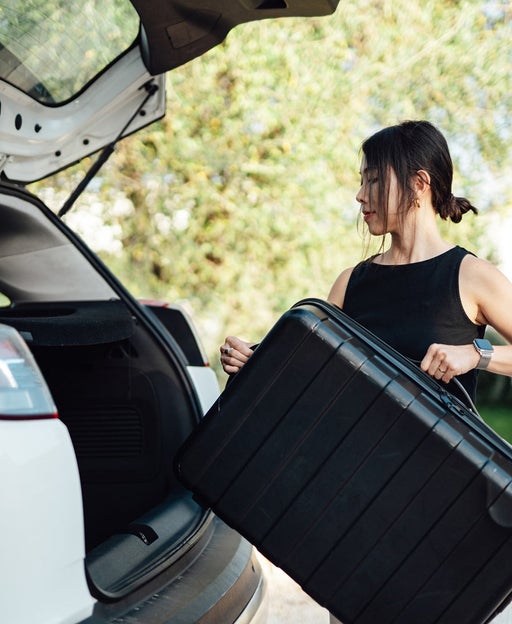 woman loading luggage into car, getting ready for a road trip