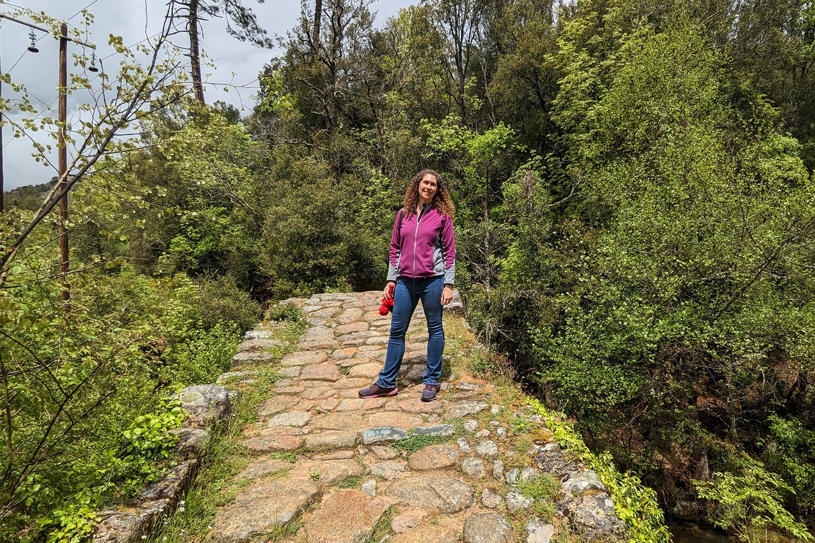 Woman in fleece jacket and jeans on a stone bridge