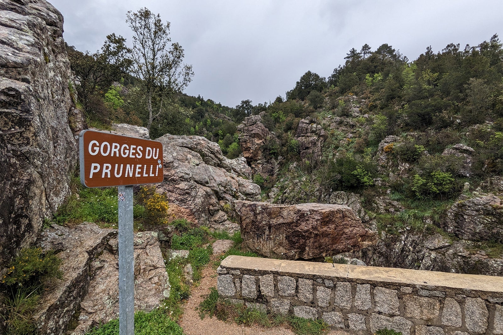 Sign reading "Gorges du Prunelli" by stone bridge