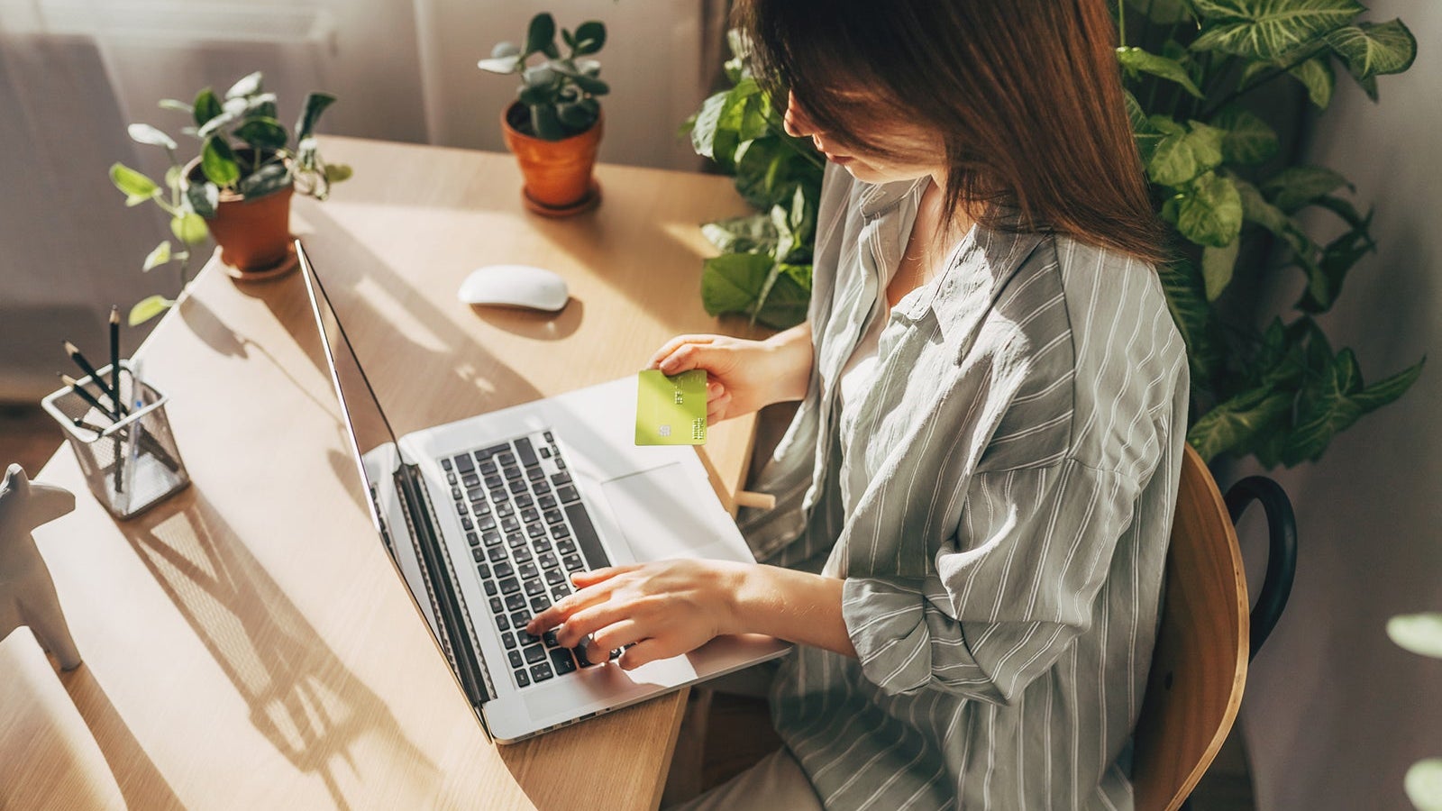 Young woman holding credit card and using laptop computer. Businesswoman working at home. Online shopping, e-commerce, internet banking, spending money, working from home concept