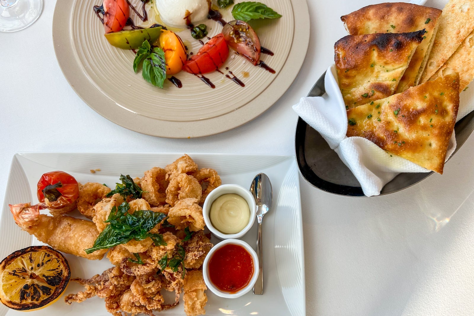Calamari and caprese salad on plates at Palo