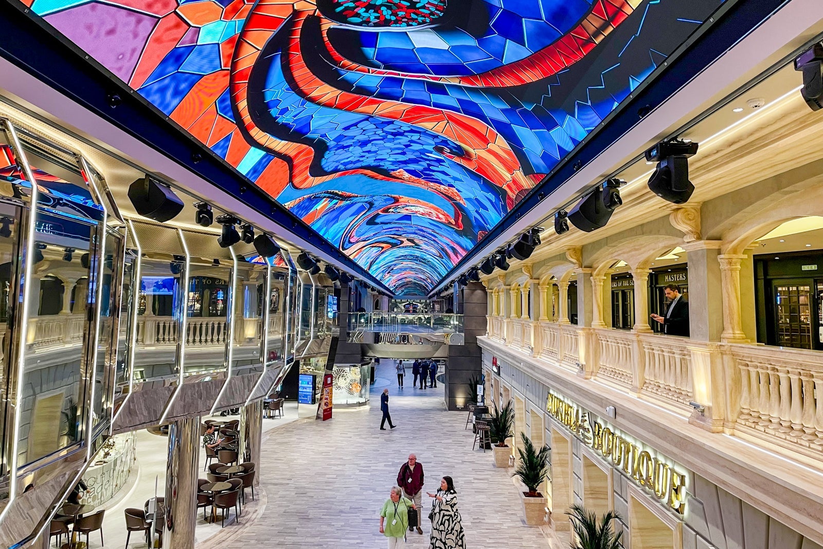 Two-level shopping gallery on cruise ship with colorful LED ceiling