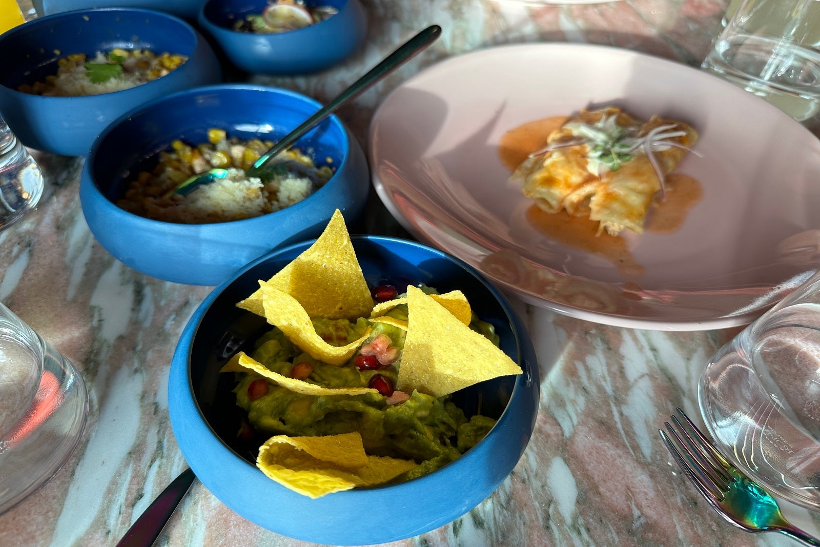 Guacamole with chips in blue bowls and chicken empanadas on a white plate