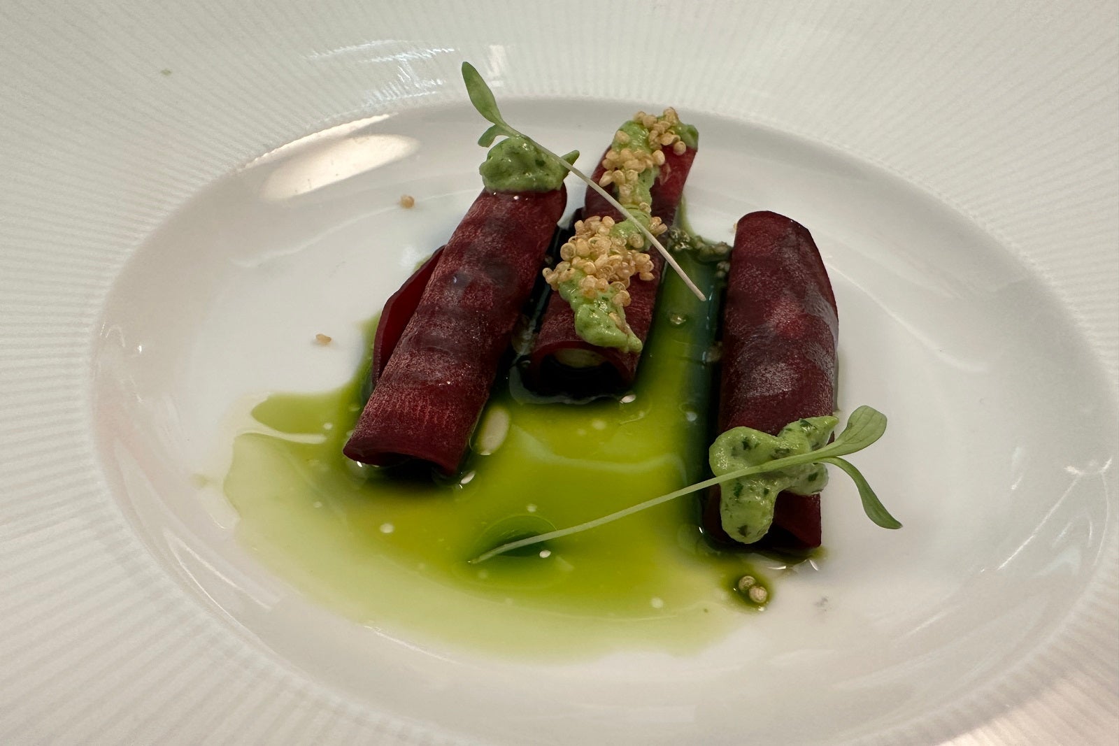 Rolled beets in green sauce on a white plate