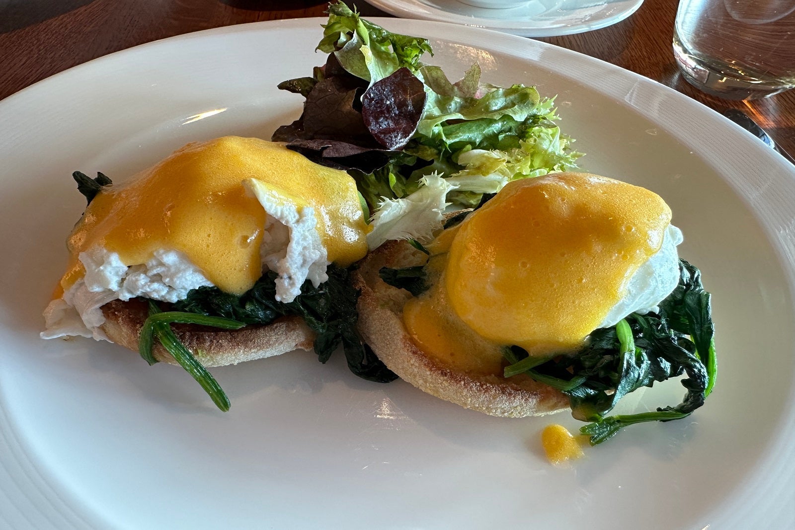 Avocado Benedict with greens on a white plate