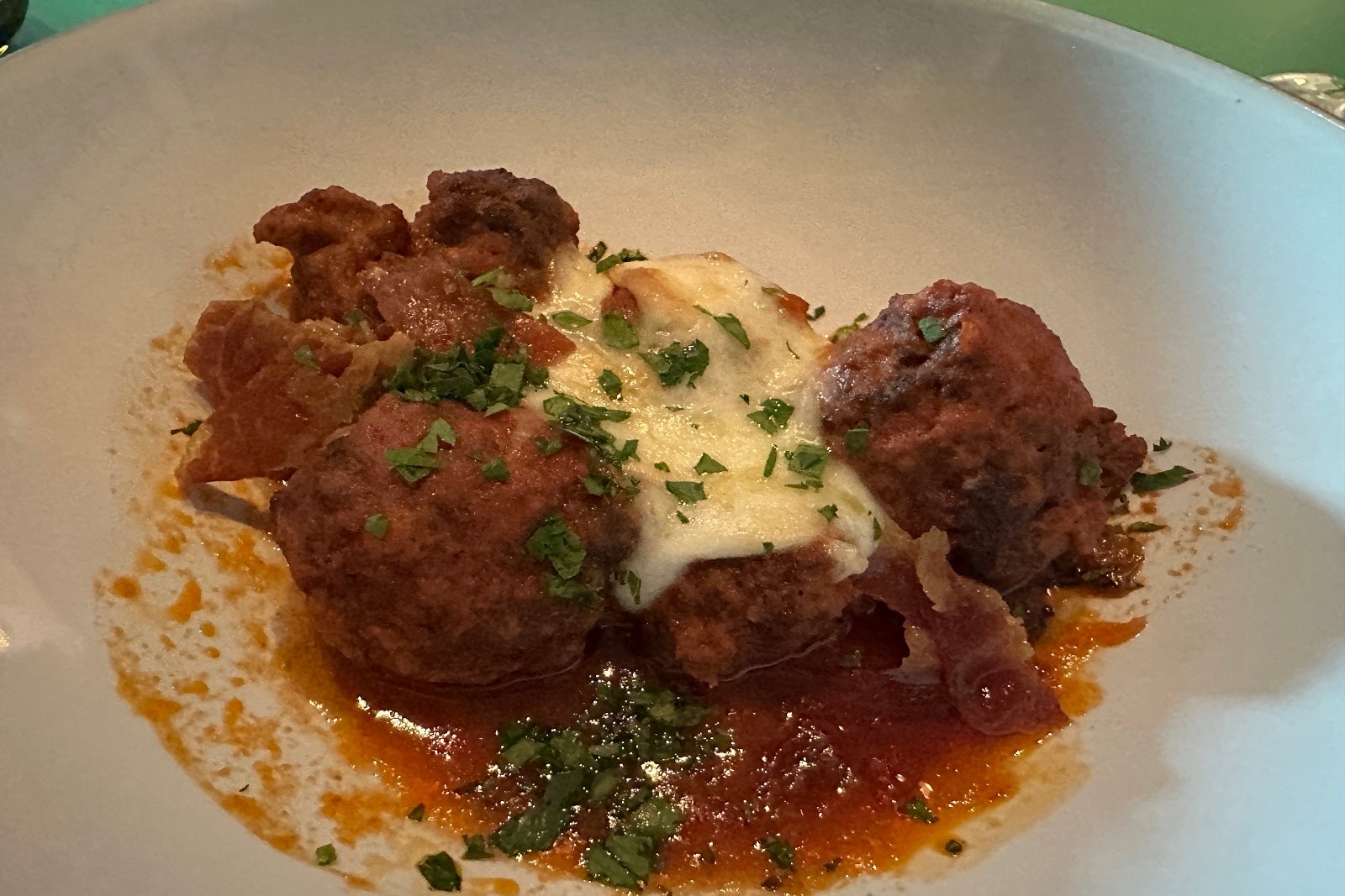 Meatballs with sauce and cheese on a white plate